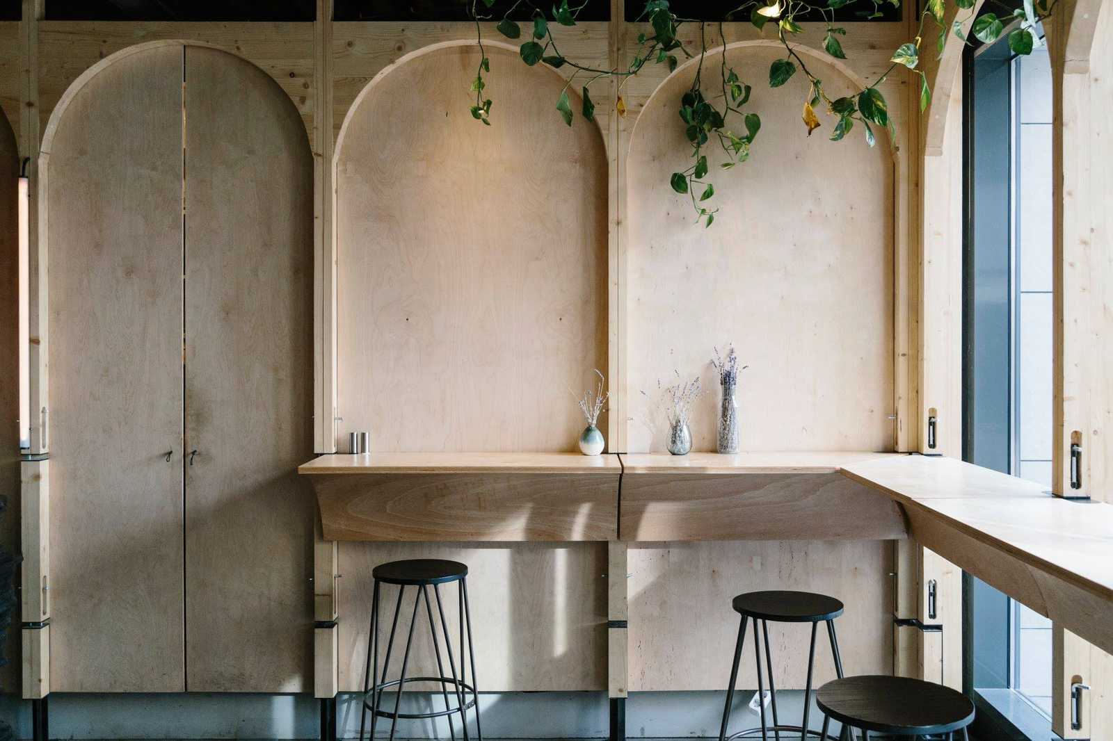 Perete din placaj de mesteacăn cu arcade în semicerc și mese cu scaune