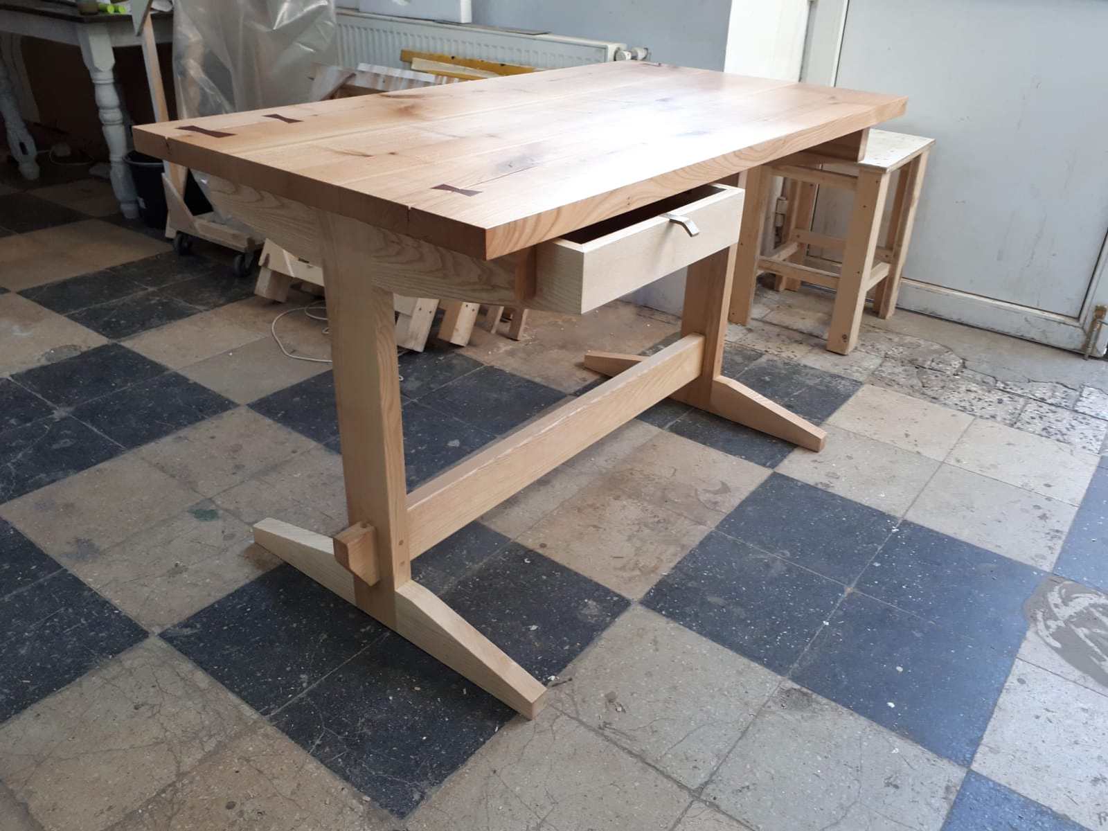 Imagine din atelier cu biroul cu blat de cireș și cadru din lemn cu tălpi și chingă de legătură