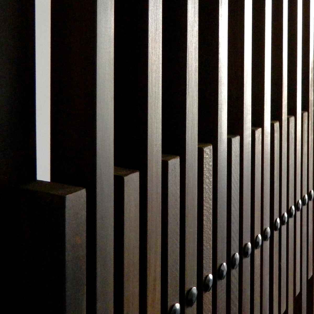 Detaliu cu nituri metalice și peretele riflat din elemente de înălțimi diferite