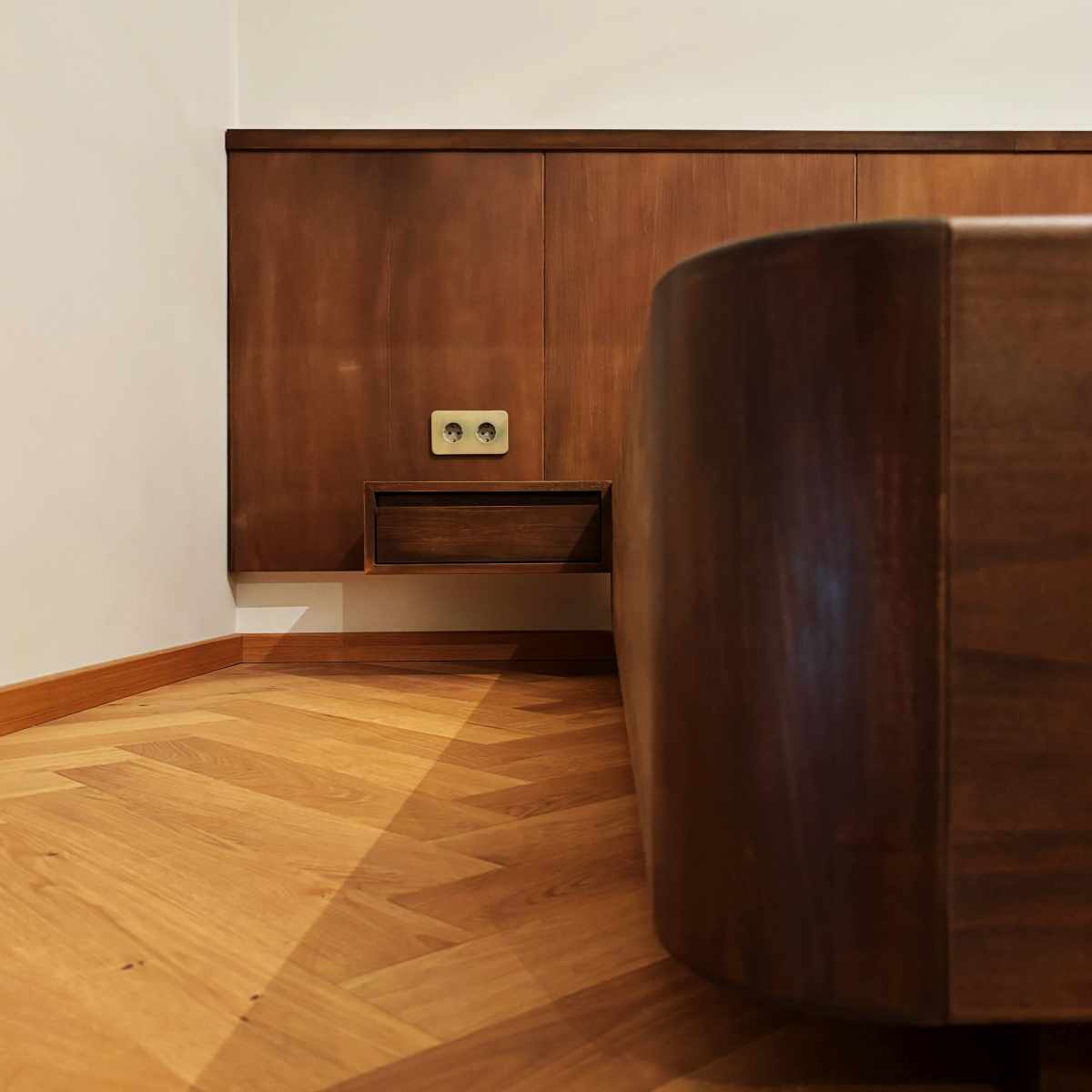 Prim plan cu cadrul patului în finisaj cafeniu închis, cu noptiera și tăblia din panouri în plan secund