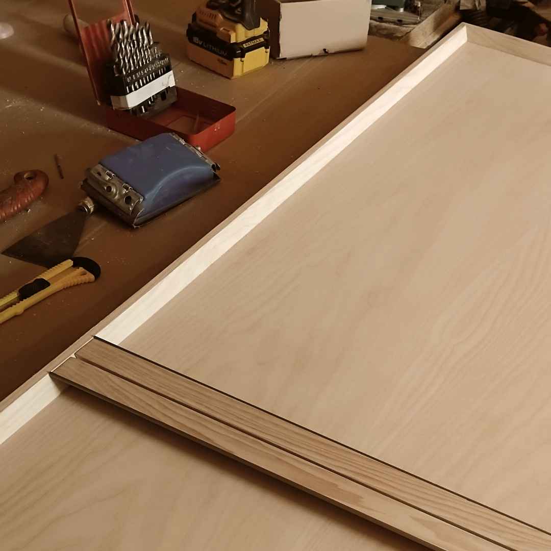 Usa mare de mobila pe un blat de lucru in atelier cu manerul de lemn integrat in rama cu insertie metalica