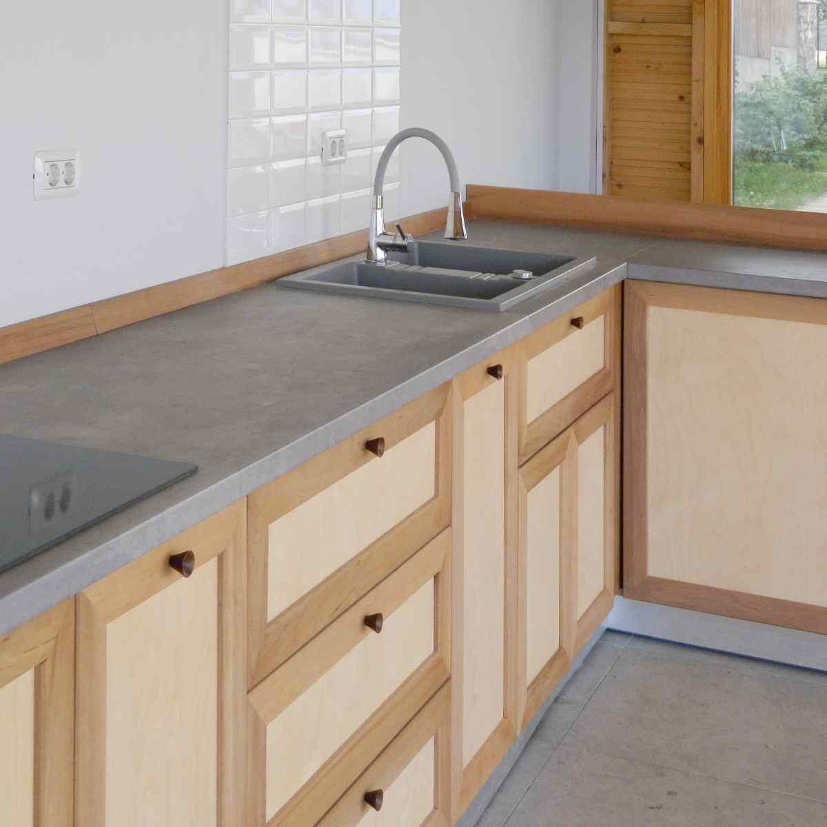 coltul dintre corpurile de bucatarie cu plita si chiuveta pe balt si manerele conice din lemn la usi si sertare