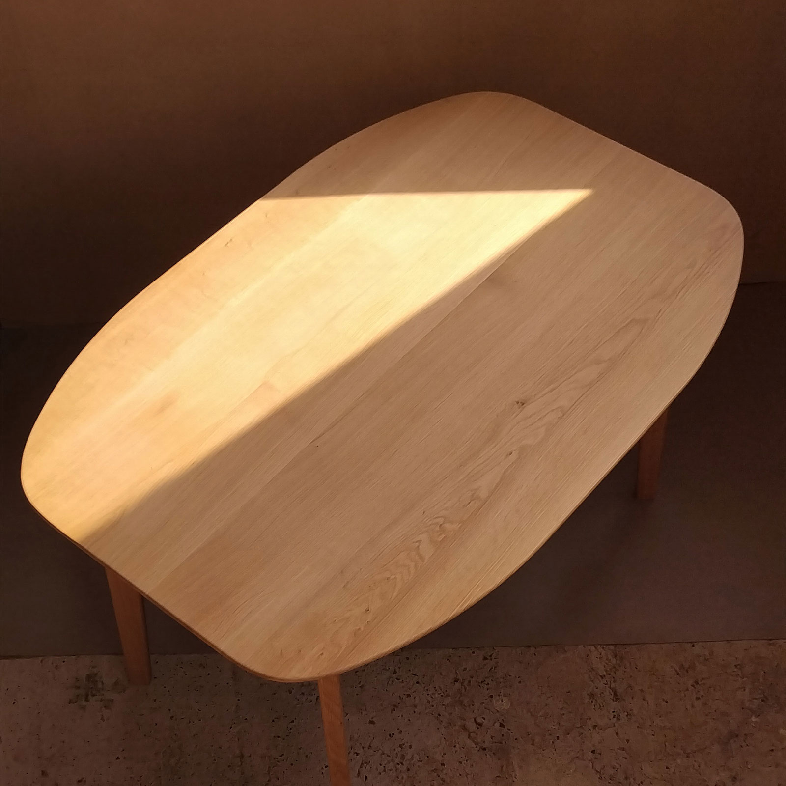 Vedere de sus cu blatul mesei in lumina naturala forma ergonomica a mesei din stejar cu fibra naturala vizibila