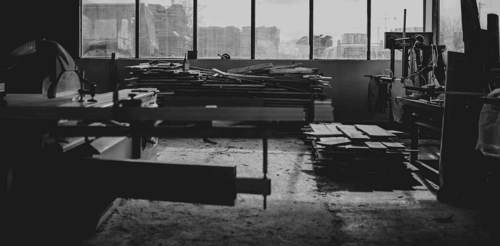 imagine din atelierul de tâmplărie cu scânduri depozitate și utilaje pentru prelucrarea lemnului